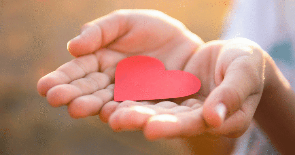 Person holding a heart shaped piece of paper.