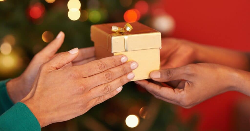 One person passing a gift box to another representing christmas gifts